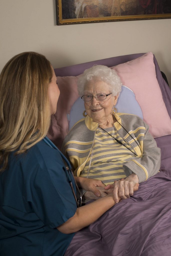 Nurse holding hands with a hospice home care patient