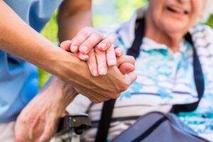 nurse holding a elderly residents hand