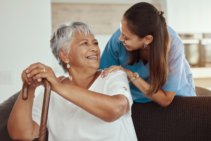 nurse bending down and smiling with older patient