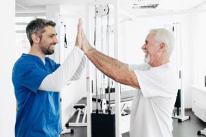 physical therapist high fiving senior patient