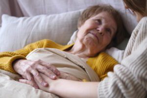 woman in hospice holding daughters hand