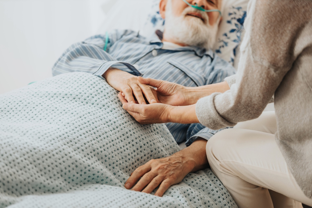 man on hospice holding family member's hand