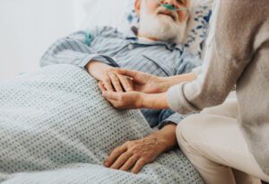 man on hospice holding woman's hand