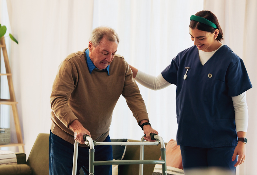 senior man using walker with caregiver nearby