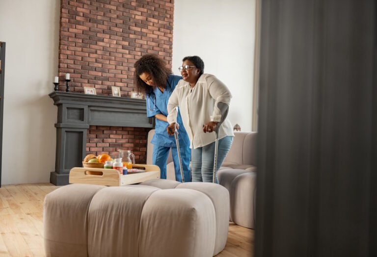 caregiver helping woman walk across a room