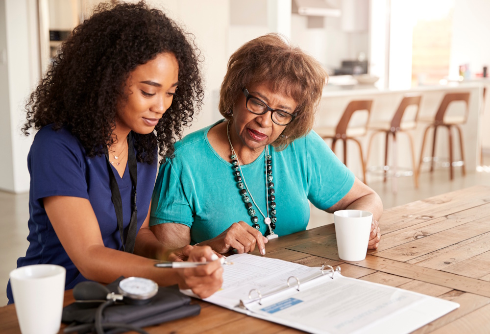 senior woman reviewing paperwork with a home health nurse