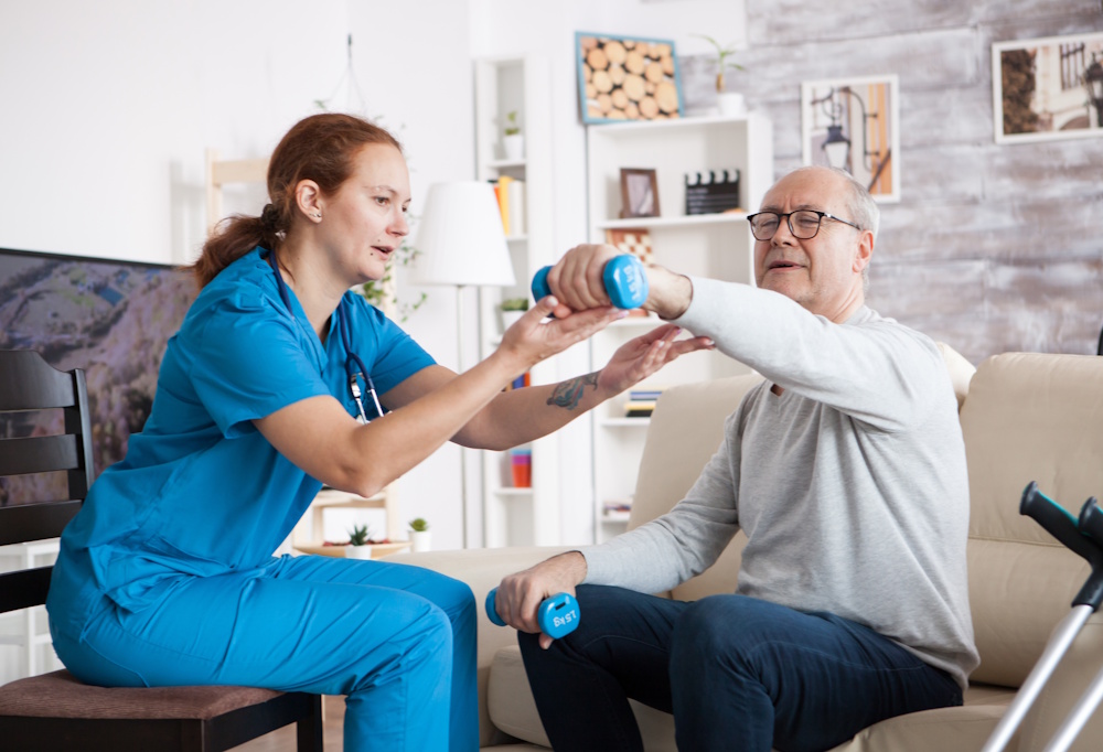 home health nurse doing physical therapy with senior man
