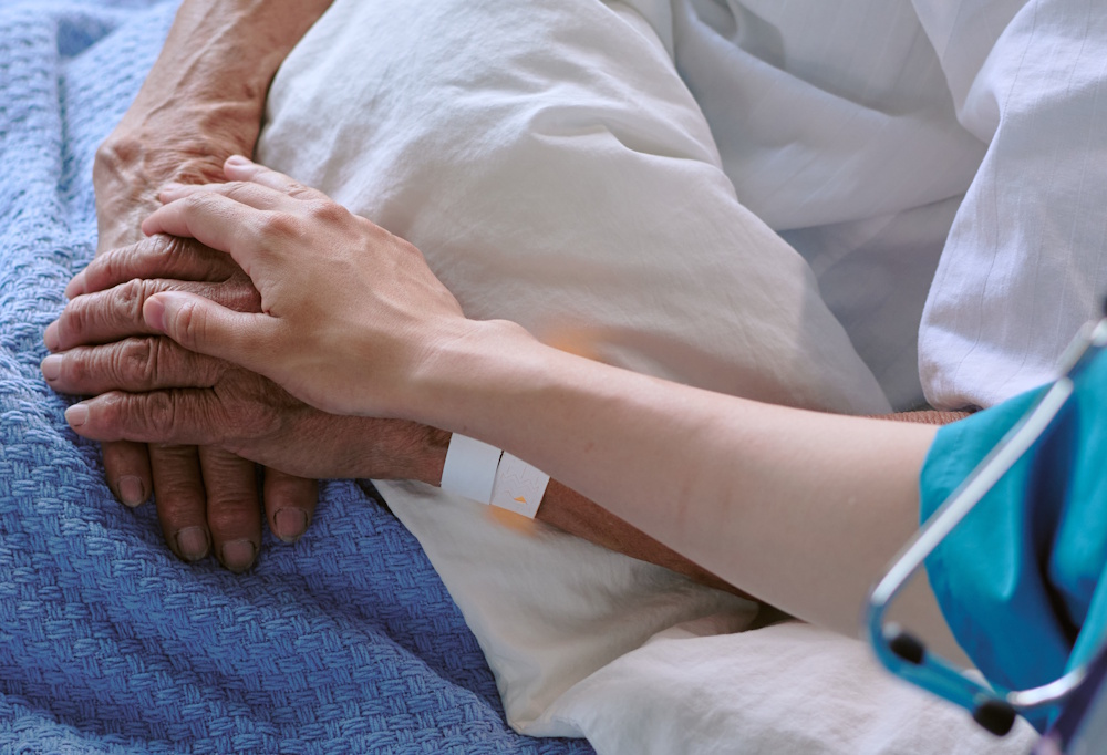 nurse holding senior man's hand