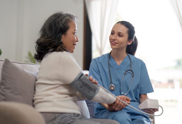 nurse using digital tonometer check blood pressure for old female at home in elderly care cardiovascular medical visit